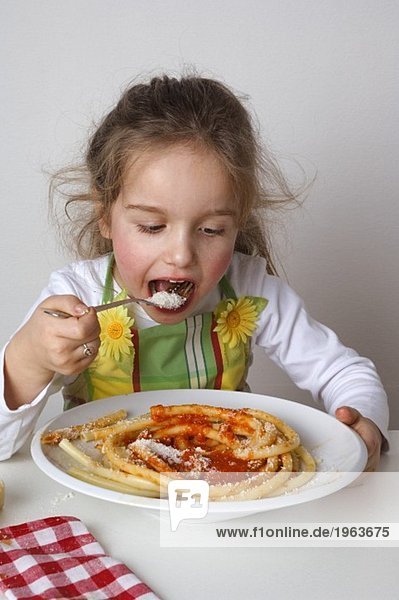 Small girl eating macaroni with tomato sauce and Parmesan