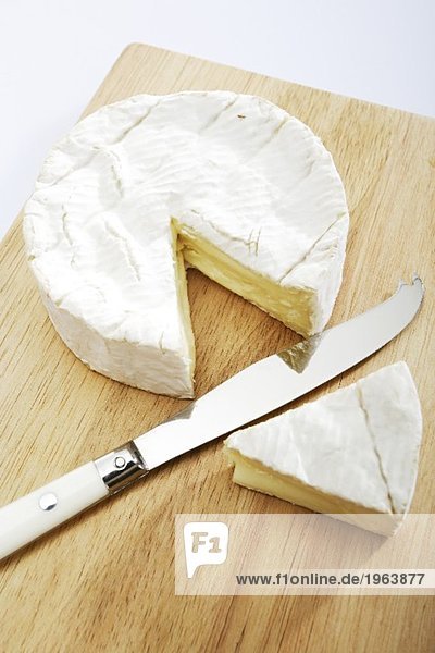 Angeschnittener Camembert auf einem Holzbrett mit Messer Angeschnittener Camembert auf einem Holzbrett mit Messer