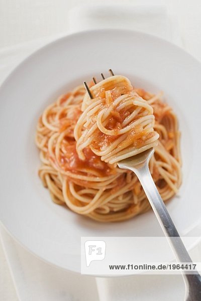 Spaghetti mit Tomatensauce auf Gabel und Teller