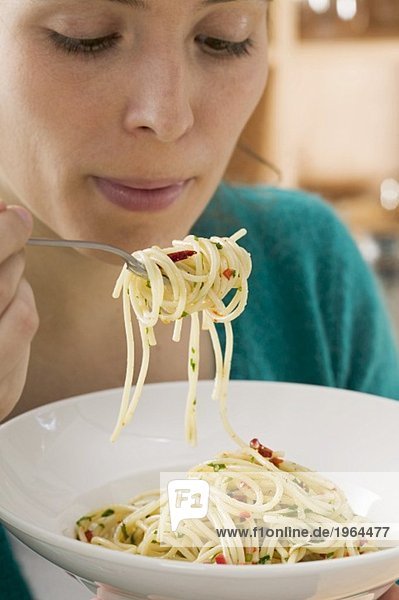 Junge Frau isst Spaghetti mit Chilischoten