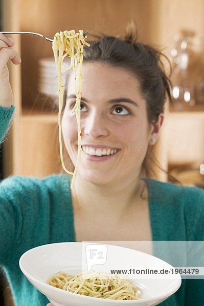Junge Frau isst Spaghetti mit Chilischoten