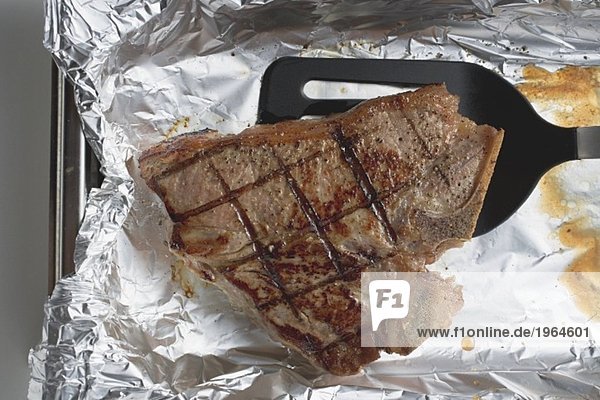 Gegrilltes T-Bone-Steak auf Alufolie mit Heber