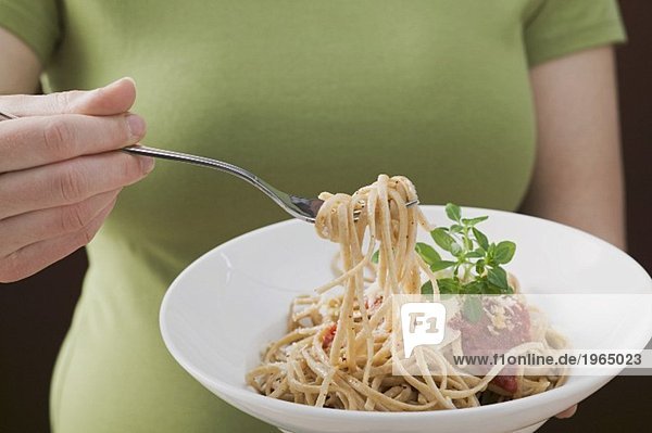 Frau isst Linguine mit Tomatensauce