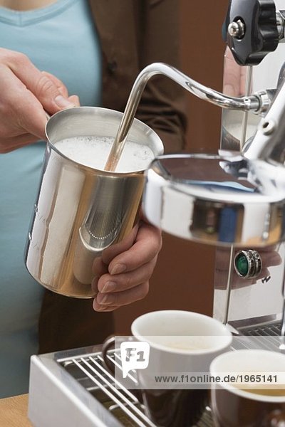 Woman frothing milk with espresso machine