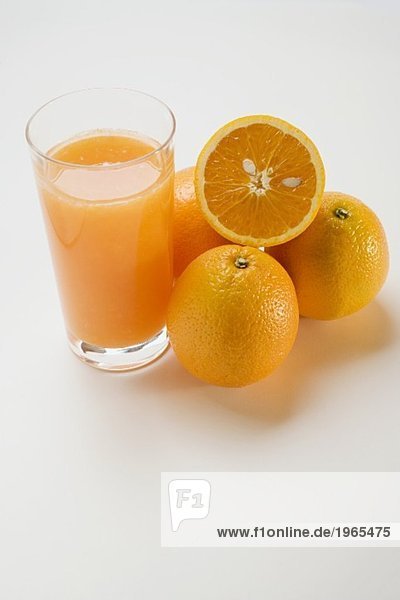 Glas Orangensaft und mehrere Orangen