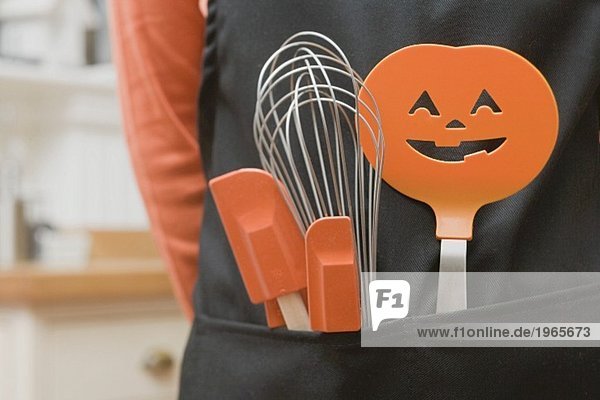 Küchenwerkzeuge für Halloween stecken in einer Schürze