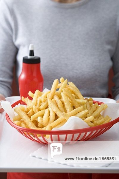 Pommes frites im Plastikkorb  Ketchup  Frau im Hintergrund