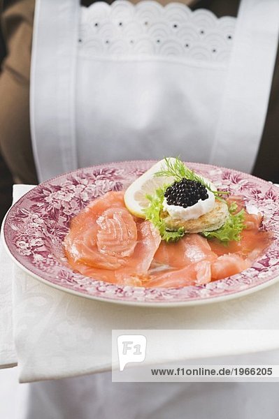Chambermaid serving smoked salmon with caviar