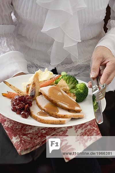 Frau serviert Putenbrust mit Beilagen zu Thanksgiving (USA)