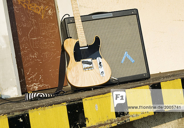 E-Gitarre steht mit Verstärker vor Lagerhalle