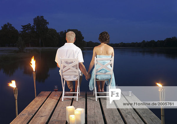 Paar  sitzen abends auf Steg an See