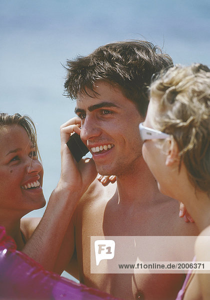 Drei Teenager am Strand  telefonieren mit Handy