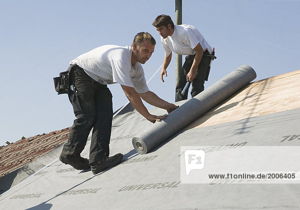 Dachdecker rollen Dachpappe auf Dach aus