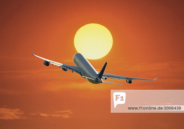 Passagierflugzeug fliegt gegen untergehende Sonne  Composing