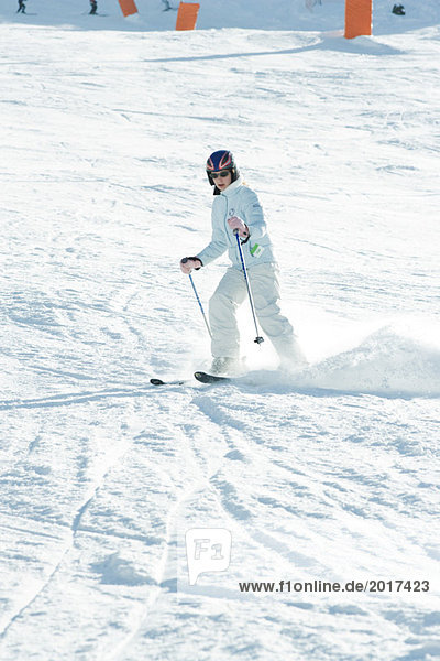 Teenage girl skiing down ski slope  full length