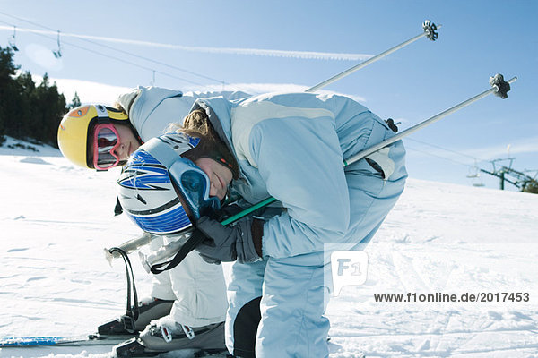 Zwei junge Skifahrer beim Bücken  Blick in die Kamera  Seitenansicht