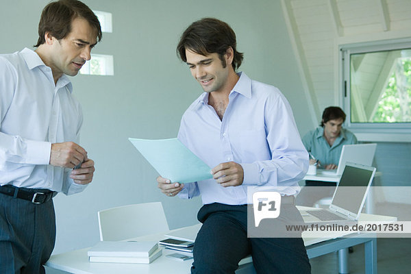 Zwei Geschäftsleute  die gemeinsam im Büro ein Dokument betrachten