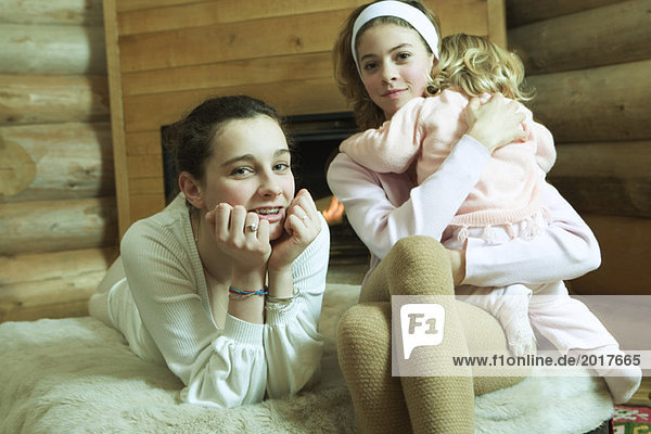 Two teen girls with little sister  smiling at camera