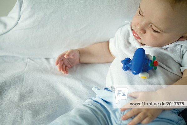 Schlafendes Baby mit Spielzeug auf dem Bauch  Hochwinkelansicht