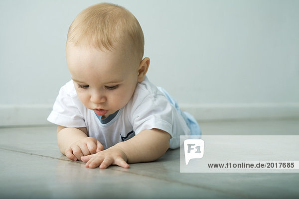 Baby auf dem Boden liegend auf die Naht im Boden schauend
