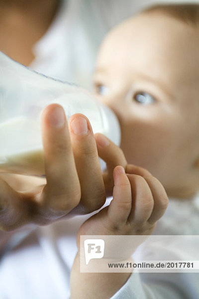 Mutterhand hält Flasche  während Baby trinkt  Nahaufnahme