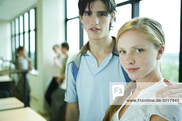 Young couple standing in college library  looking at camera  portrait