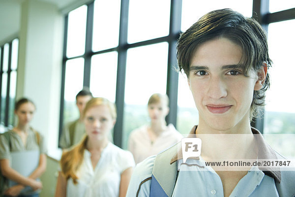 Group of college students  focus on young man in foreground  smiling at camera
