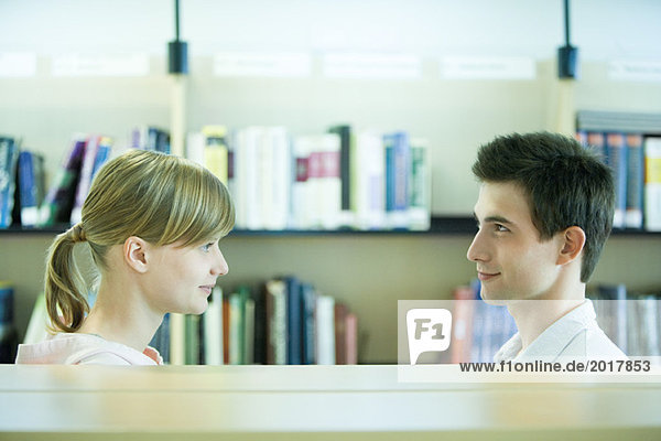 Male and female college students face to face in library