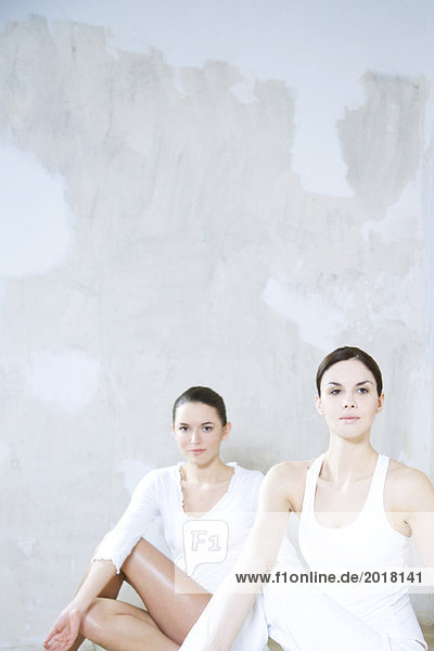 Zwei junge Frauen beim Yoga  eine schaut in die Kamera.