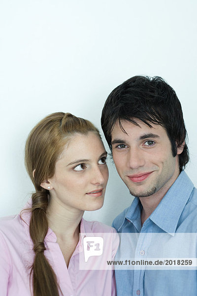 Young couple  man smiling at camera  woman looking at man with admiration  portrait