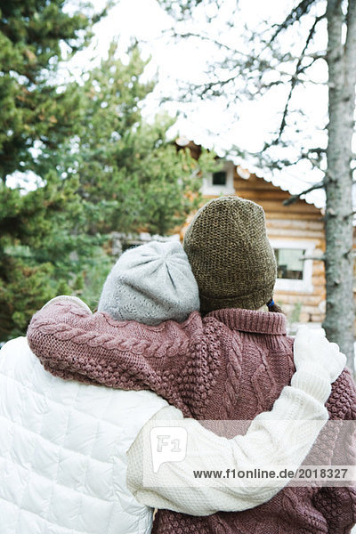 Zwei junge Freunde umarmend  in Winterkleidung  Rückansicht