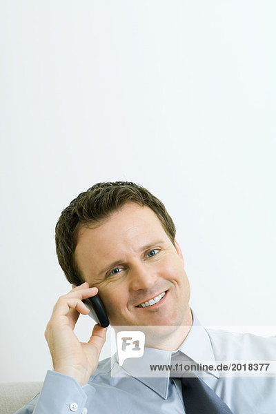 Businessman using cell phone  smiling at camera  portrait