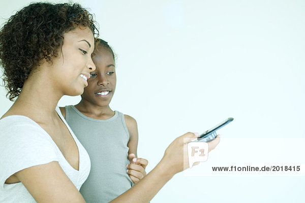 Mutter und Tochter schauen zusammen aufs Handy  lächelnd