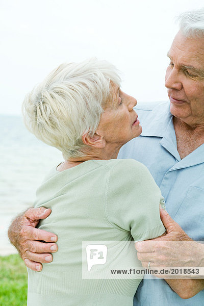 Seniorenpaar spricht  Mann hält Frau in den Armen