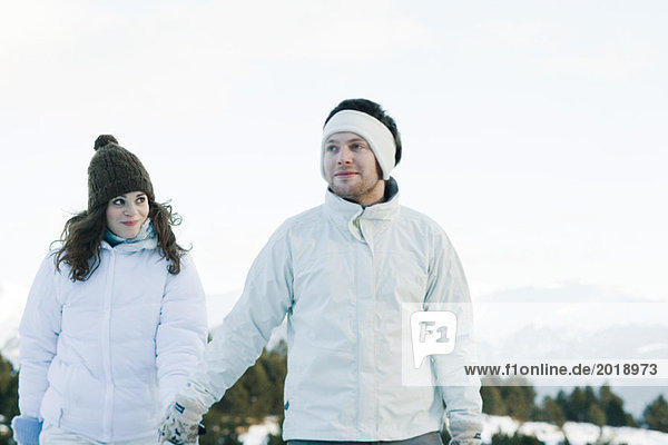 Young couple in ski clothes holding hands