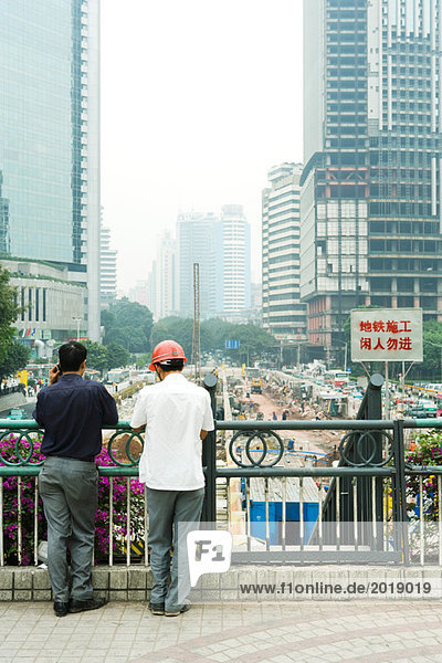China  Provinz Guangdong  Guangzhou  zwei Männer schauen über die Baustelle  Rückansicht