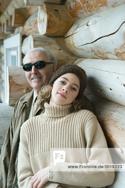 Grandfather and teen granddaughter smiling at camera together  portrait