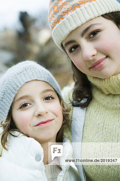 Two sisters smiling at camera  wearing knit hats  portrait