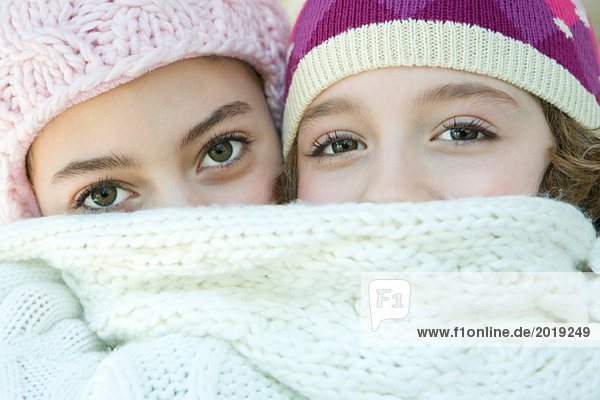 Two young friends covering mouths with scarf  looking at camera  portrait