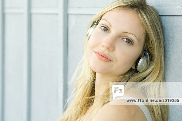 Young woman listening to headphones  smiling at camera  portrait
