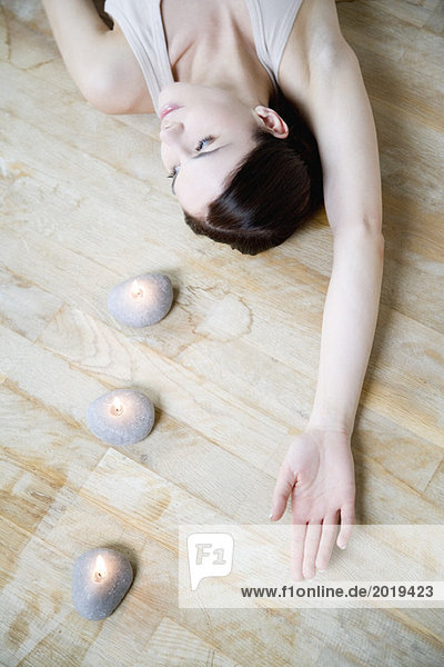 Frau auf dem Boden liegend mit Kerzen  Arm erhoben  wegschauend