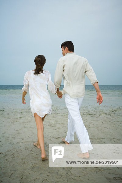 Vater und Tochter gehen Hand in Hand am Strand  Rückansicht  Gesamtlänge