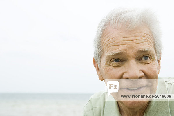 Senior man smiling  looking away  headshot  ocean in background