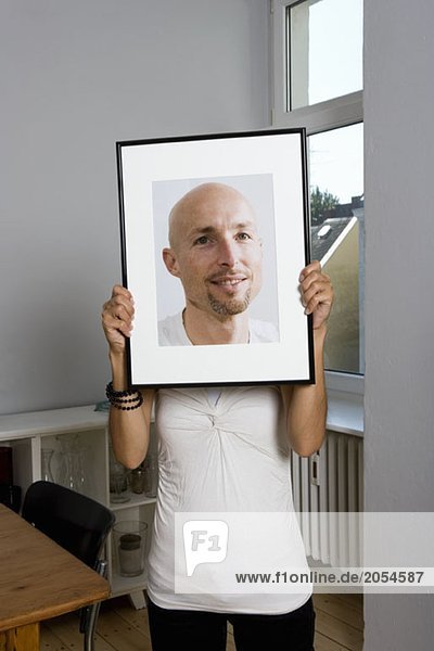 Eine Frau hält ein gerahmtes Foto vor ihr Gesicht.