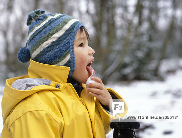 A young boy licking a snowball
