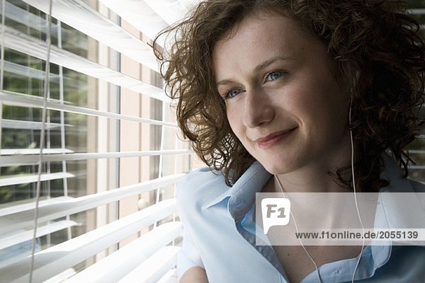 A woman wearing headphones and looking out a window