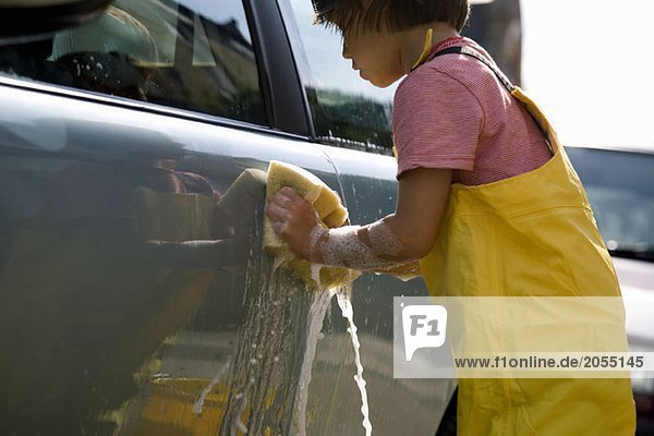 Detail of a young boy washing a car