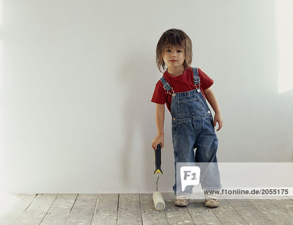 A young boy holding a paint roller