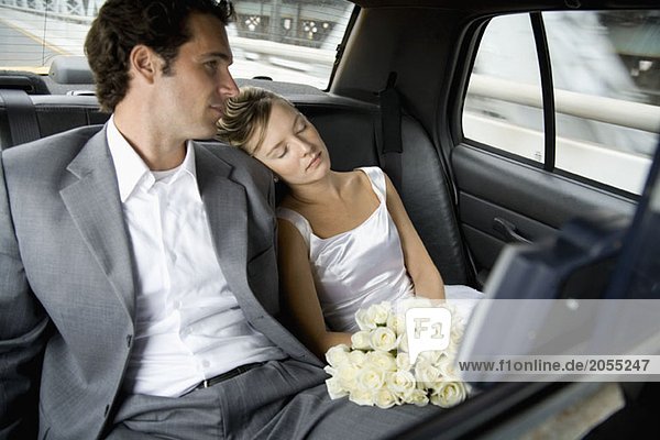 Eine Braut und ein Bräutigam  die sich im Auto entspannen.