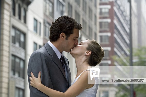 A bride and groom kissing in the street